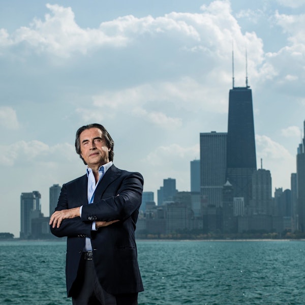 Riccardo Muti steht am Ufer des Chicago River, im Hintergrund die Stadtsilhouette.