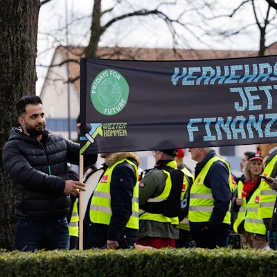 Demonstranten stehen vor dem Tagungshotel der Verkehrsministerkonferenz. Sie halten ein Plakat hoch mit der Aufschrift "Verkehrswende jetzt finanzieren".