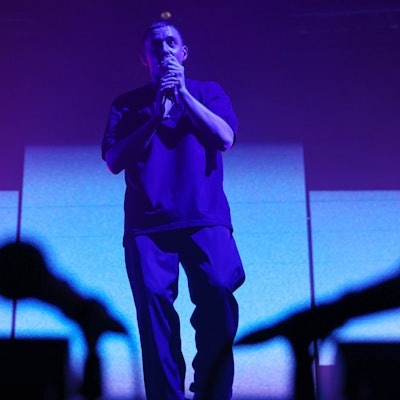 Sänger Dermot Kennedy steht auf der Bühne im Palladium. Er hält ein Mikrofon in der Hand. Zwei Mikrofone sind verschwommen im Vordergrund.