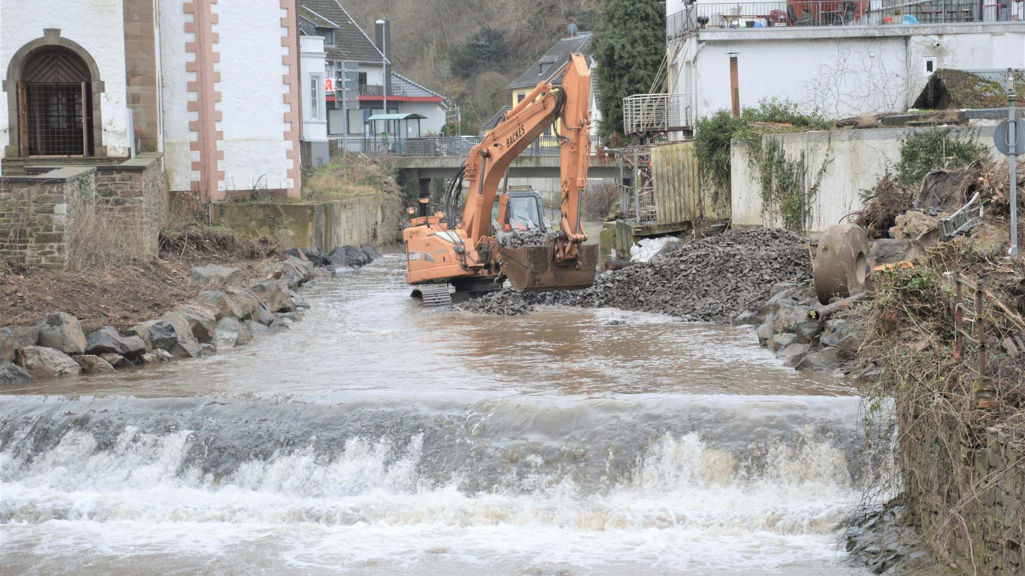 Ein Bagger steht in der Urft in Gemünd und beseitigt Schäden, die die Flut angerichtet hat.