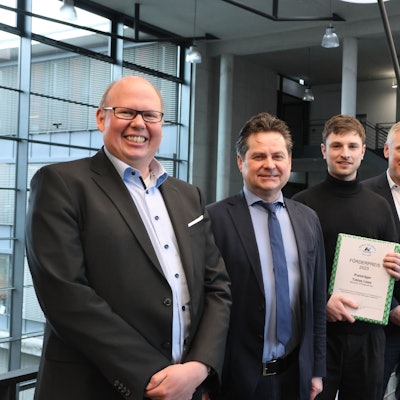 Zu sehen ist eine Preisverleihung an einen jungen Mann.