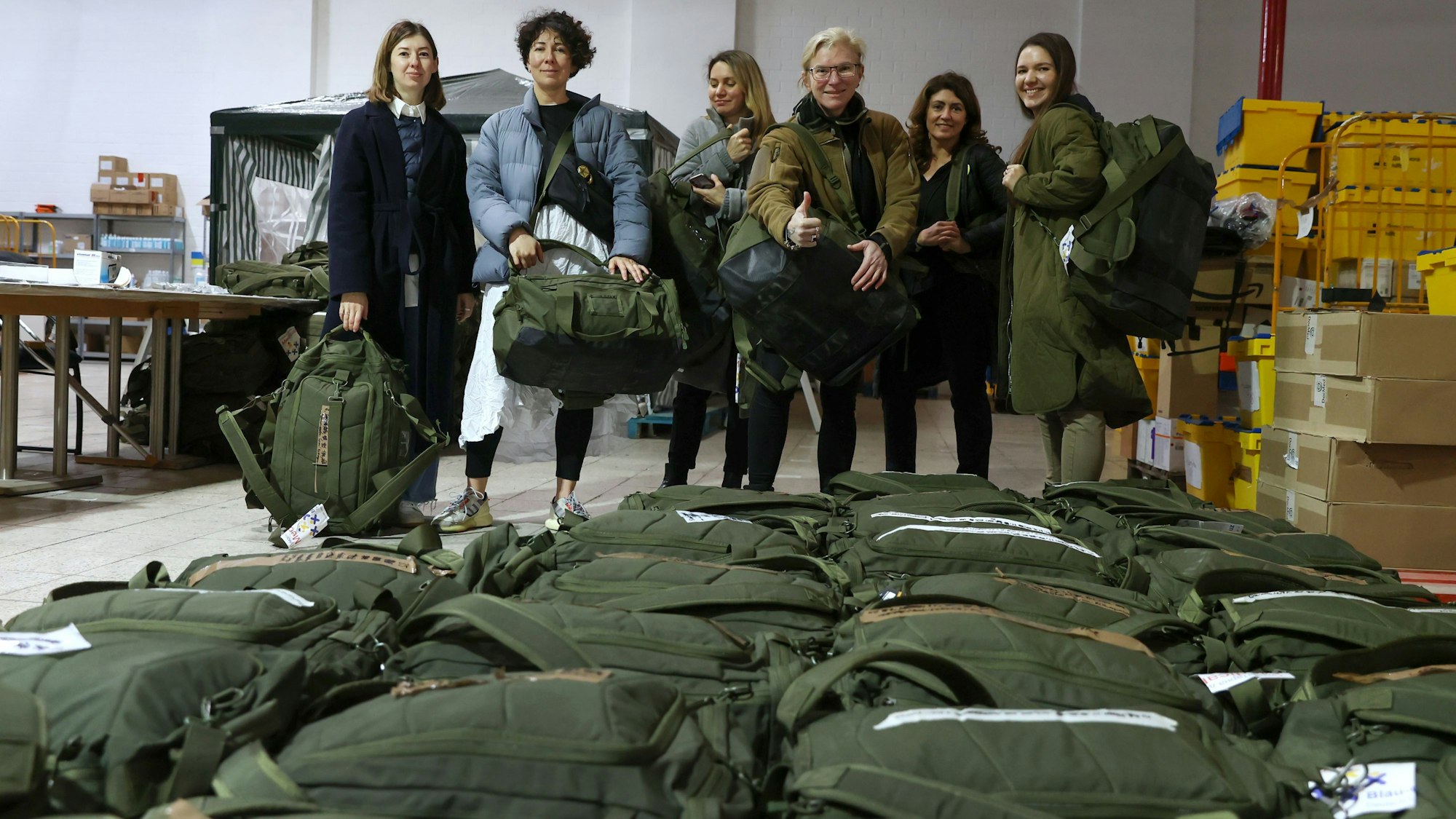 Taira (mitte) mit den Helferinnen des Blau-Gelben Kreuzes in der Lage in Köln. Sie haben sich Notfallrucksäcke umgehängt, vor ihnen liegen dutzende weitere Rucksäcke auf dem Boden.