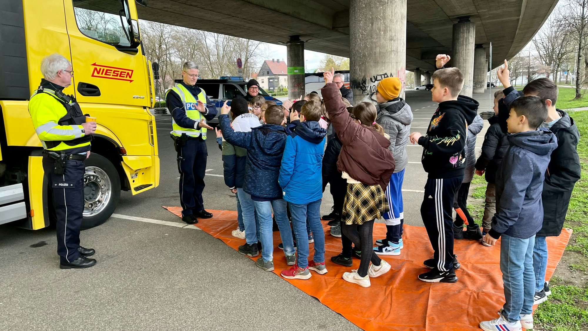Kinder auf einer Plane, die den toten Winkel verdeutlicht.