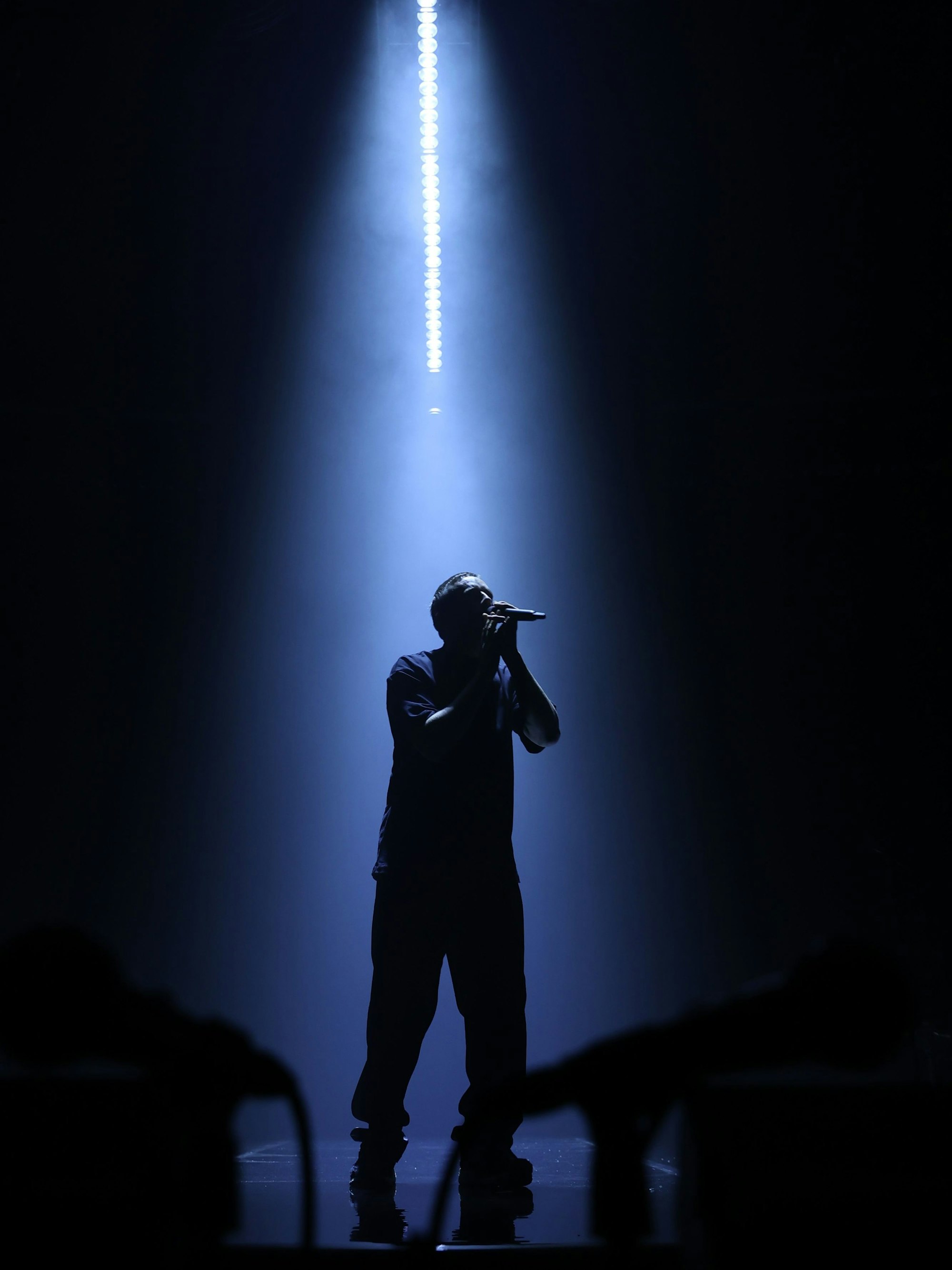 Dermot Kennedy steht im Lichtkegel auf der Bühne. Es ist nur seine Silhouette zu sehen. Er singt ins Mikrofon.