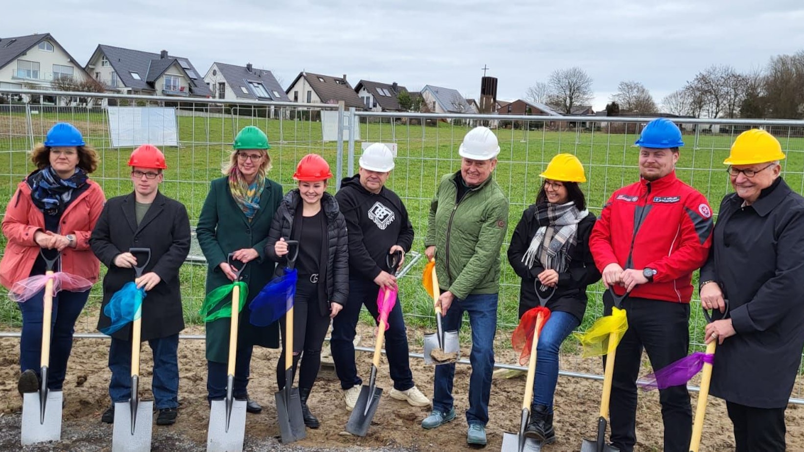 Mehrere Personen, darunter der Architekt Heinz Hennes und die Bürgermeisterin, stehen mit einem Spaten in der Hand auf dem Gelände der zukündtigen Kita.