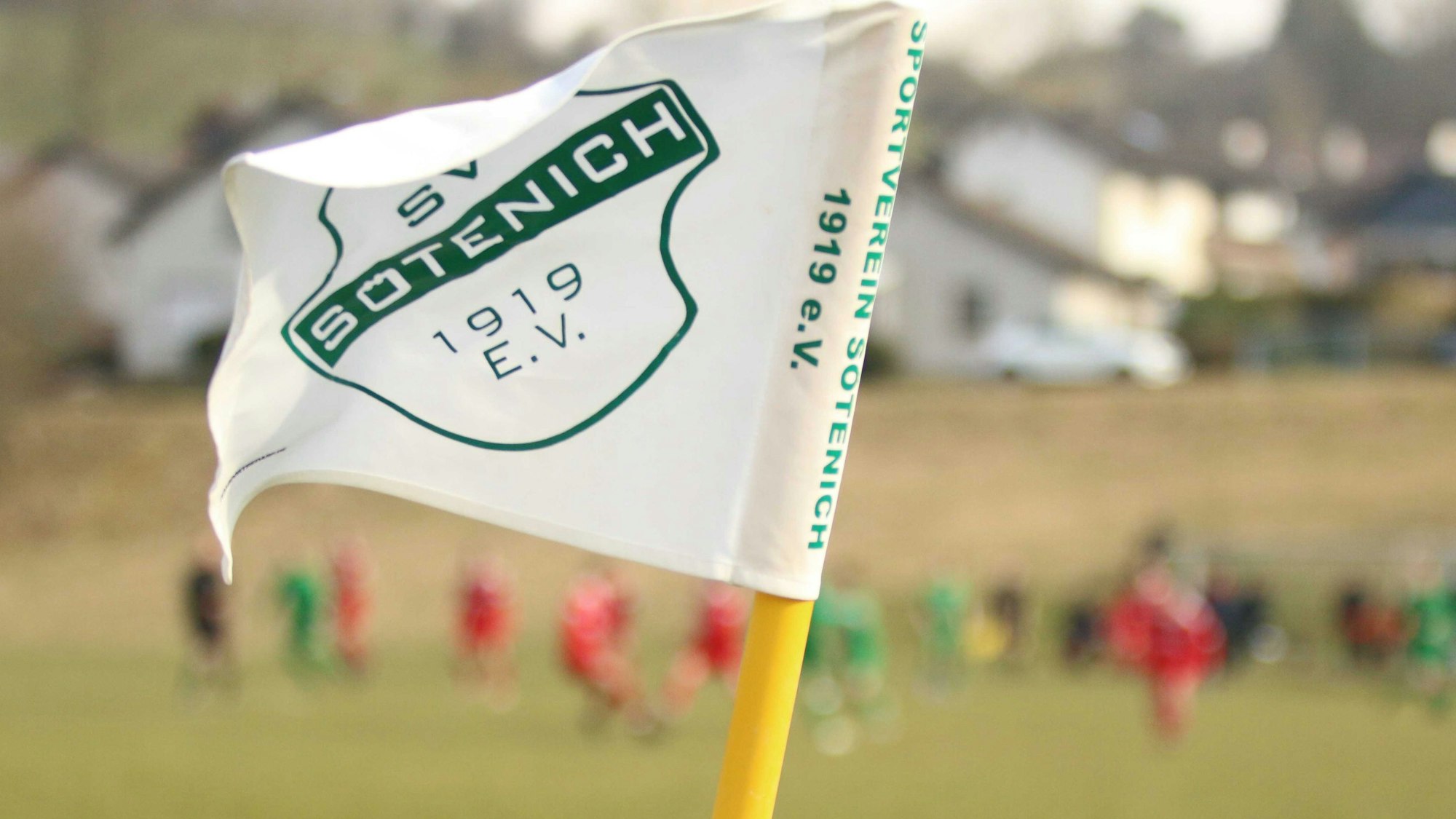Die Fahne des SV Sötenich weht am Rande des Fußballplatzes.