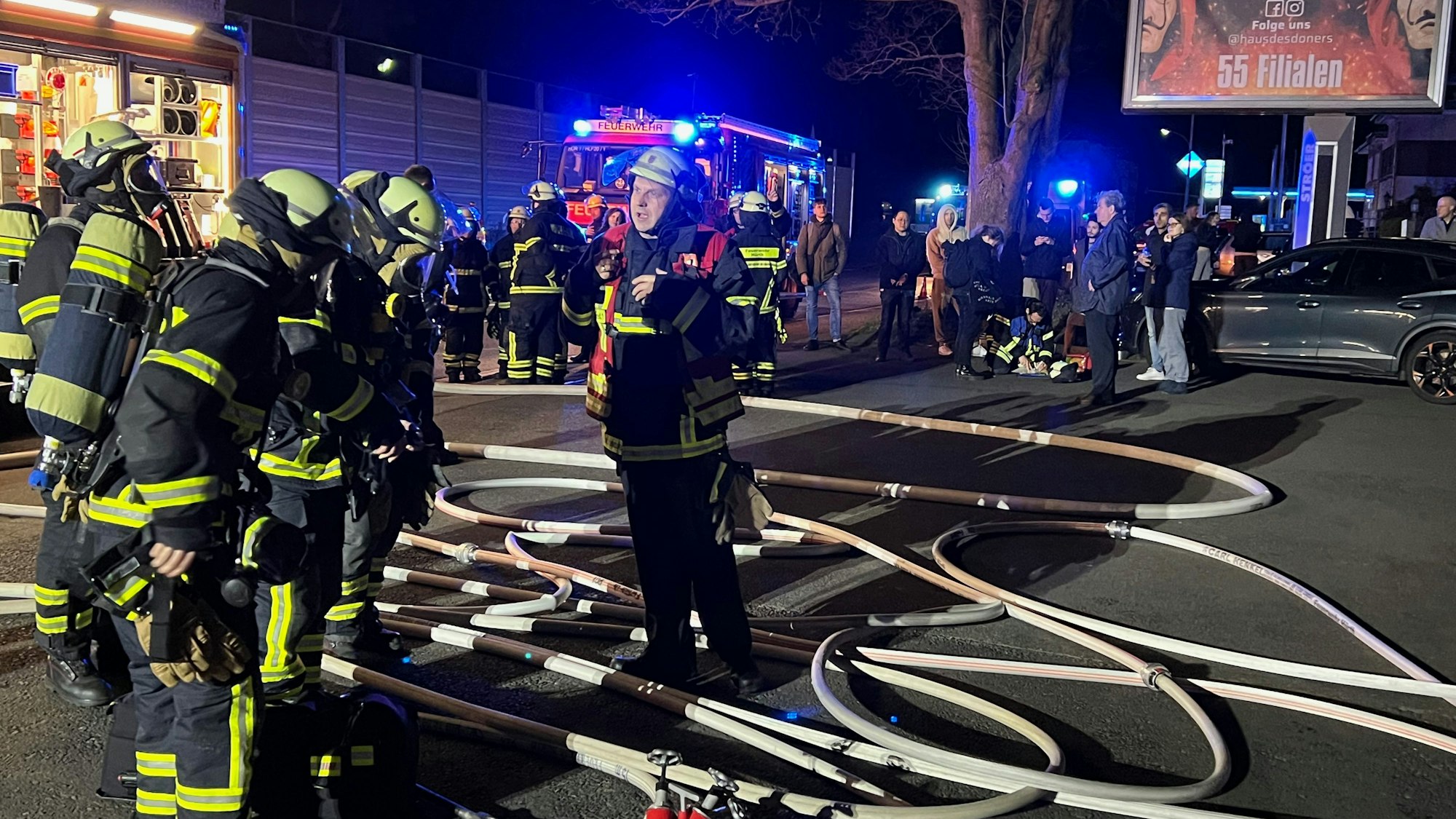 Feuerwehrleute stehen mit Schläuchen auf einer Straße