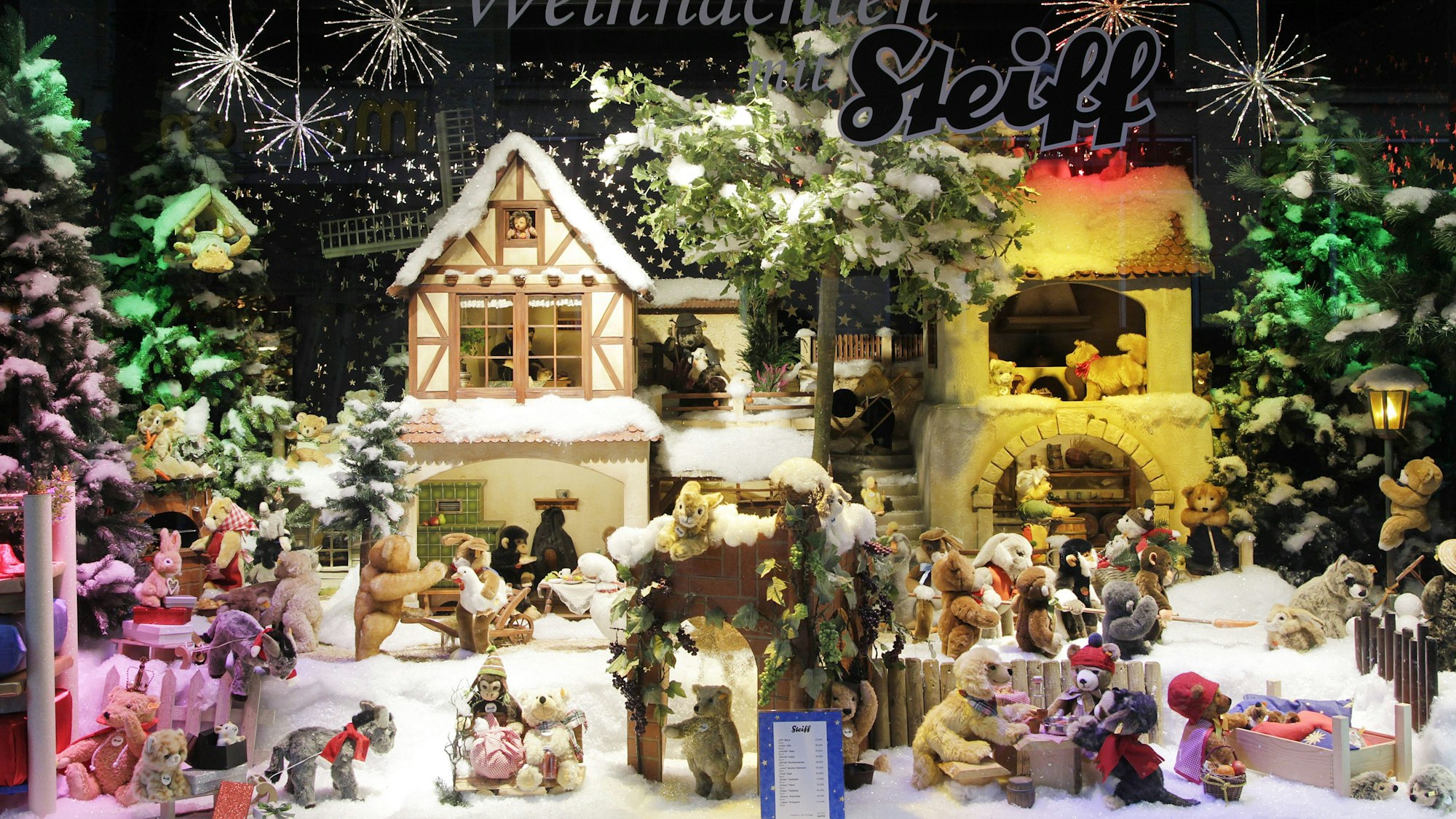 Weihnachtliche Schaufensterdekoration mit zahlreichen Steiff-Stofftieren in einer Winterlandschaft.