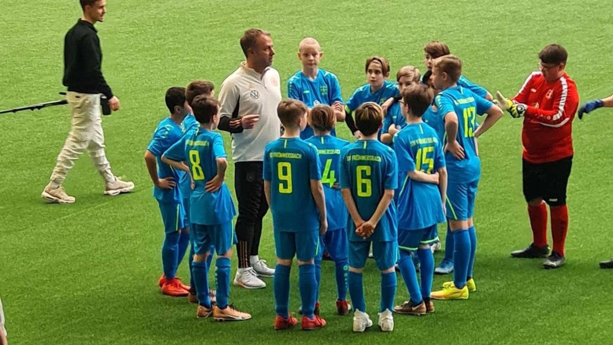 Hansi Flick steht im Kreis mit den Frömmersbacher Spielern.