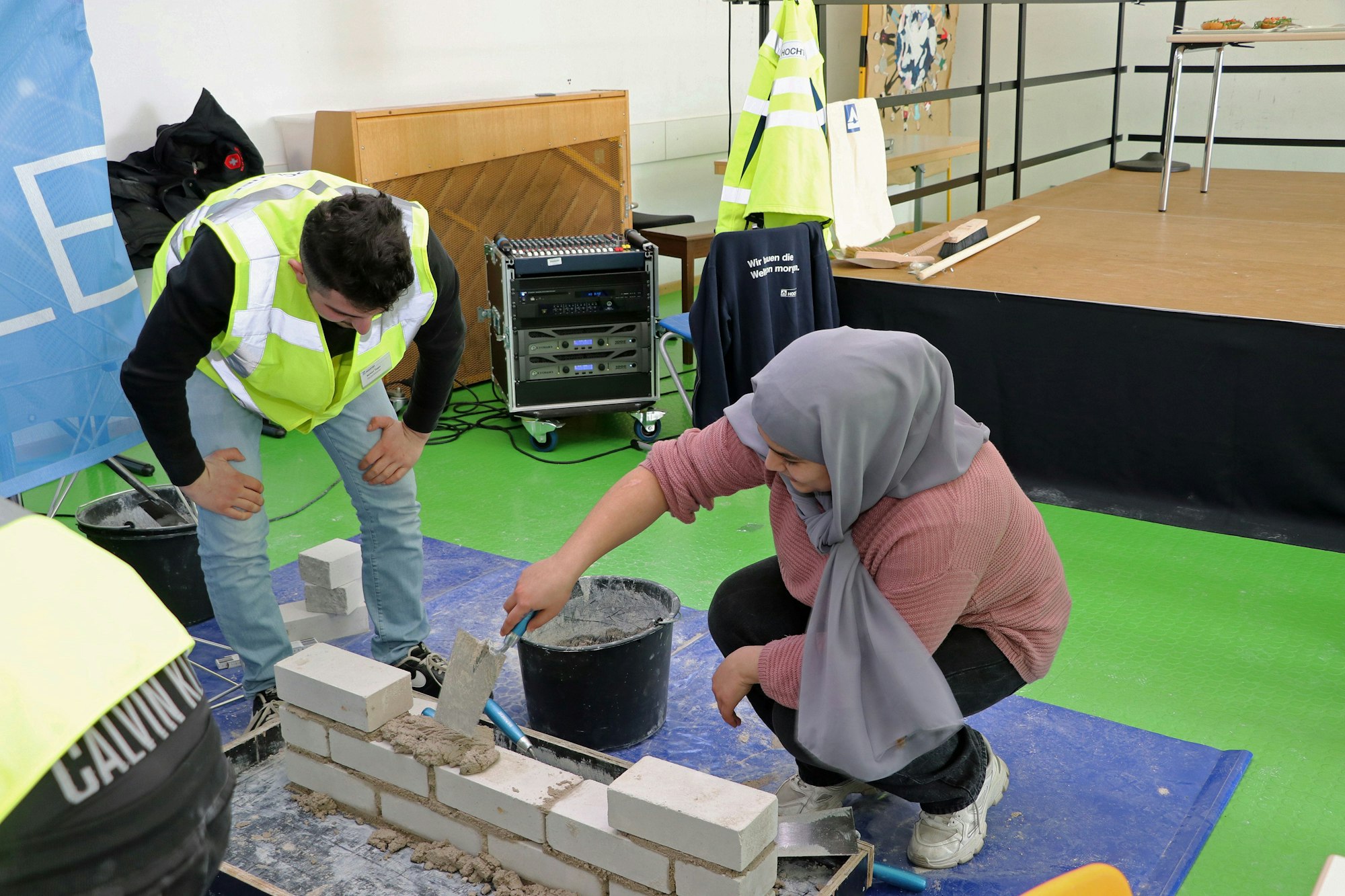 Das Bild zeigt eine Schülerin, die eine Mauer aus Steinen baut.