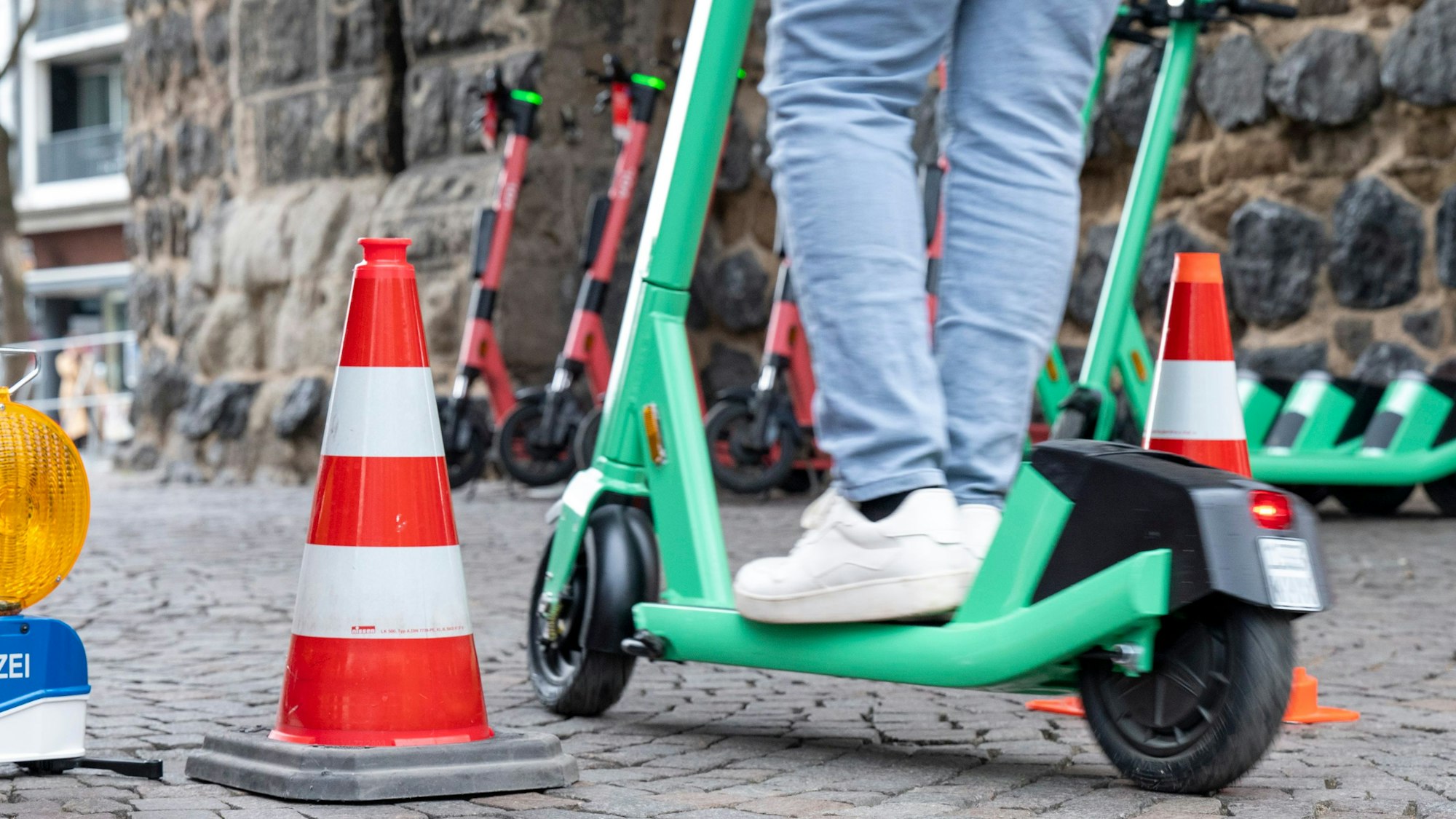 Ein E-Scooter-Fahrer umfährt zwei Pylone auf dem Rudolfplatz in Köln.