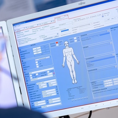 Eine Telenotärztin sitzt in der Rettungsleitstelle der Feuerwehr vor einem Bildschirm und ist mit Rettungssanitätern verbunden, die eine Schlaganfallpatientin behandeln.