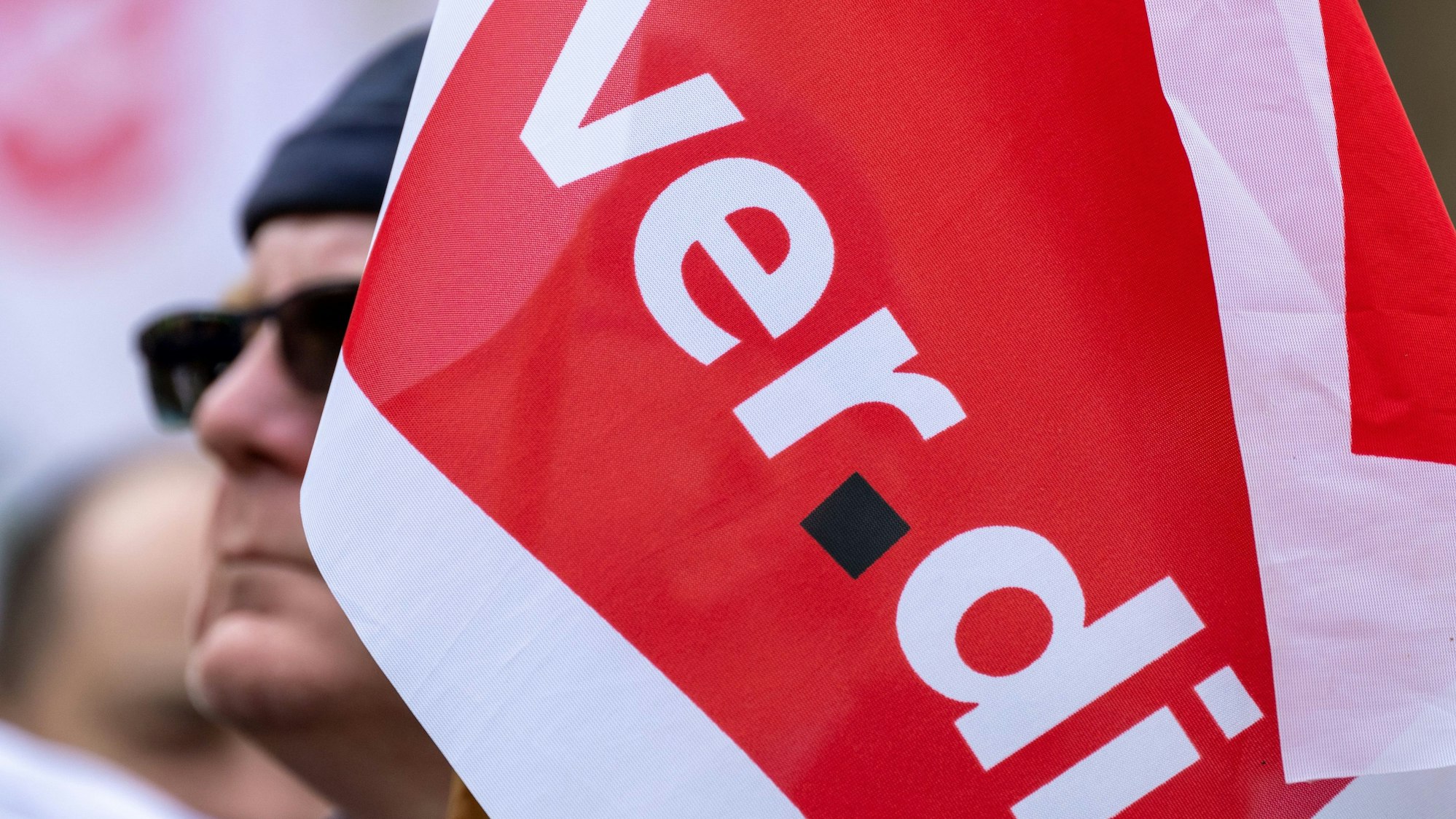 Eine Fahne der Dienstleistungsgewerkschaft Verdi schwenkt ein Teilnehmer einer Warnstreikkundgebung in Halle/Saale.