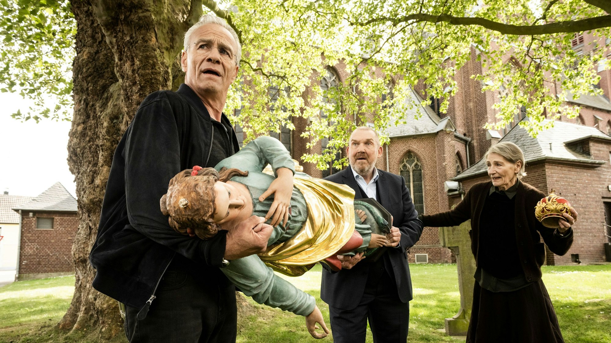 Max Ballauf (Klaus J. Behrendt) und Freddy Schenk (Dietmar Bär) tragen eine Madonnen-Figur. Karin Bongartz (Barbara Nüsse) träg ihre Krone.
