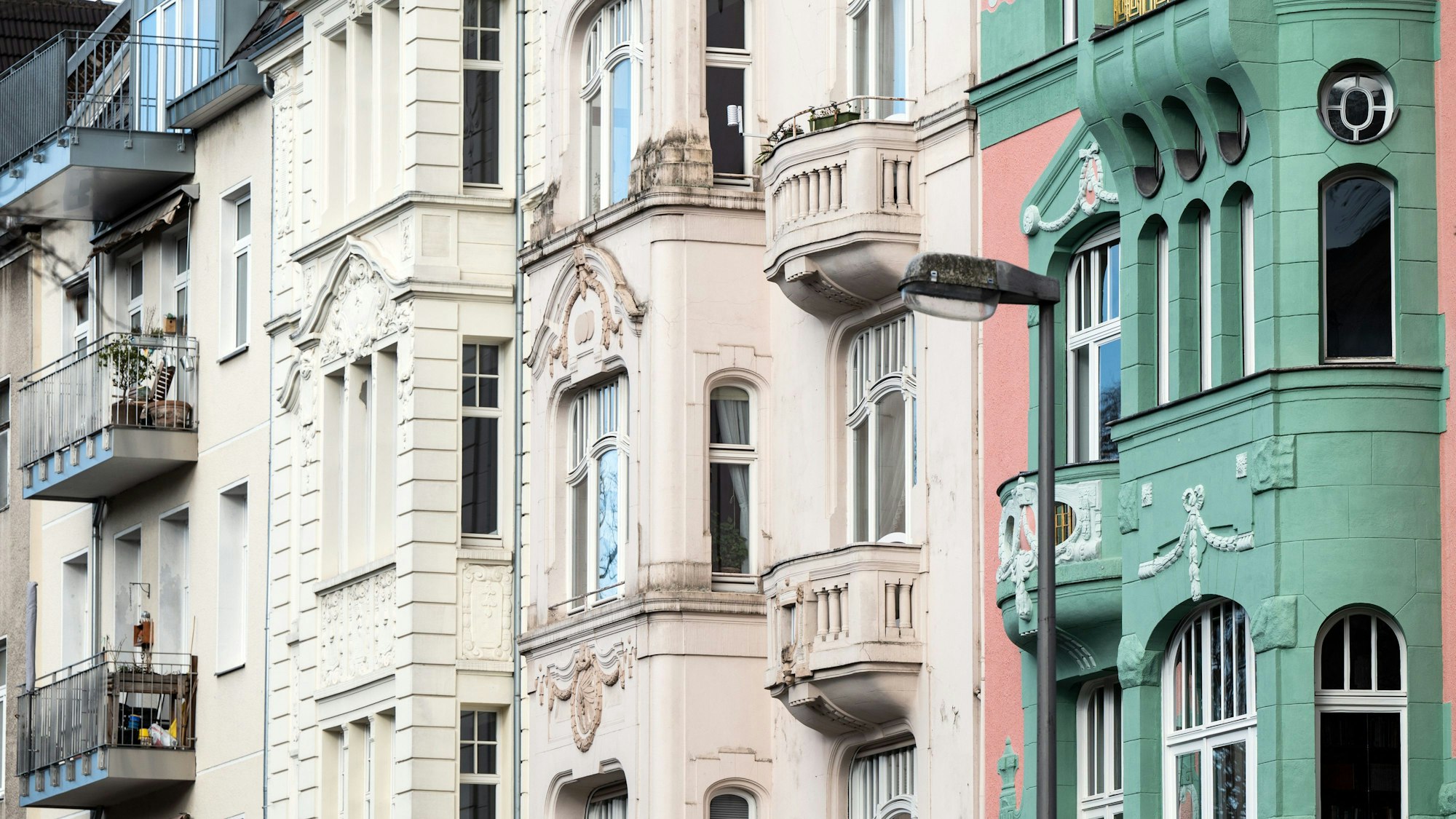 In Pastelltönen gestrichene Wohngebäude stehen an einer Straße in Köln.