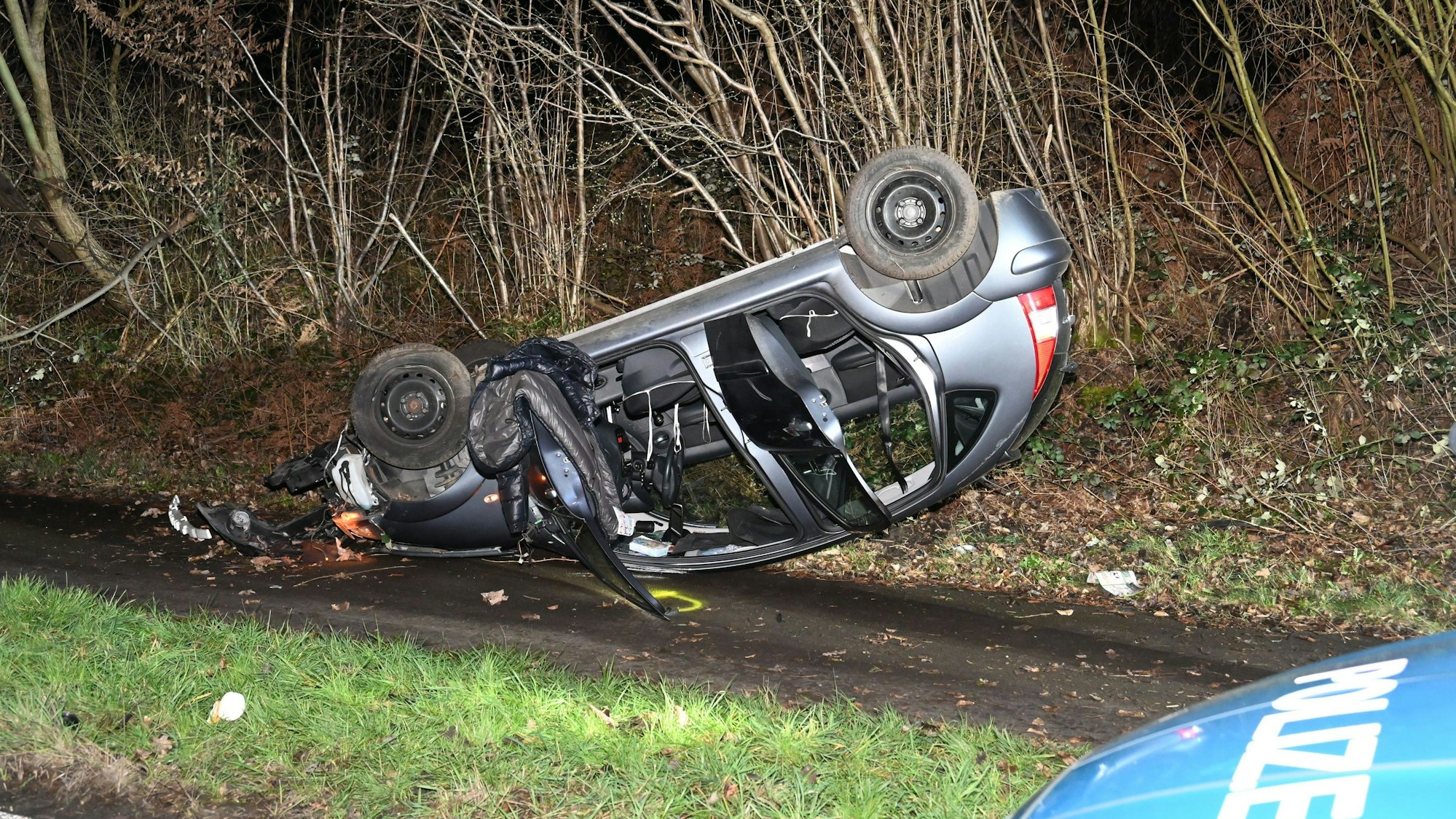 Der Wagen liegt auf dem Dach am Straßenrand.