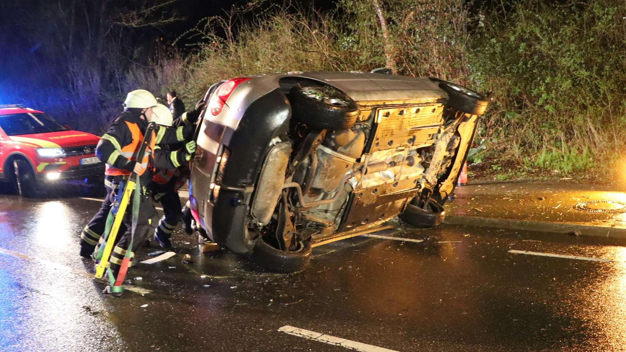 Einsatzkräfte der Feuerwehr und Polizei versuchen, den Pkw auf die Räder zu kippen.