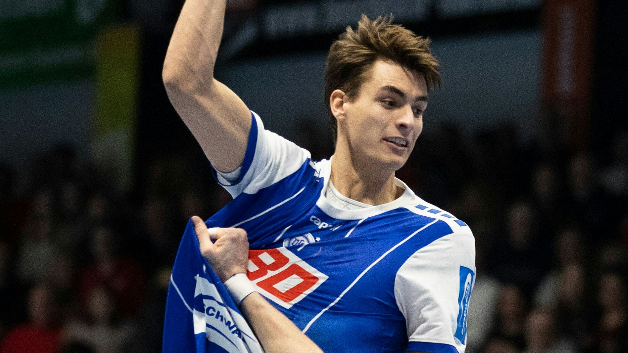 Handballer Julian Köster hebt mit dem Ball in der Hand zum Sprungwurf ab.