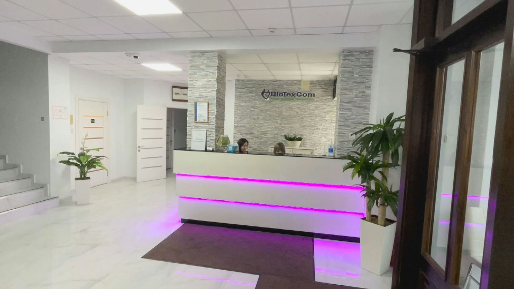 Zwei Mitarbeiterinnen sitzen hinter einem weißen Empfangstresen im Eingangsbereich der Biotexcom-Klinik in Kiew.