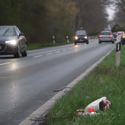 Das Foto zeigt die Rodenkirchener Straße in Wesseling. Dort war in der Nacht auf Sonntag ein 20-Jähriger ums Leben gekommen. Im Grünstreifen liegen Blumen, Kerzen wurden aufgestellt.