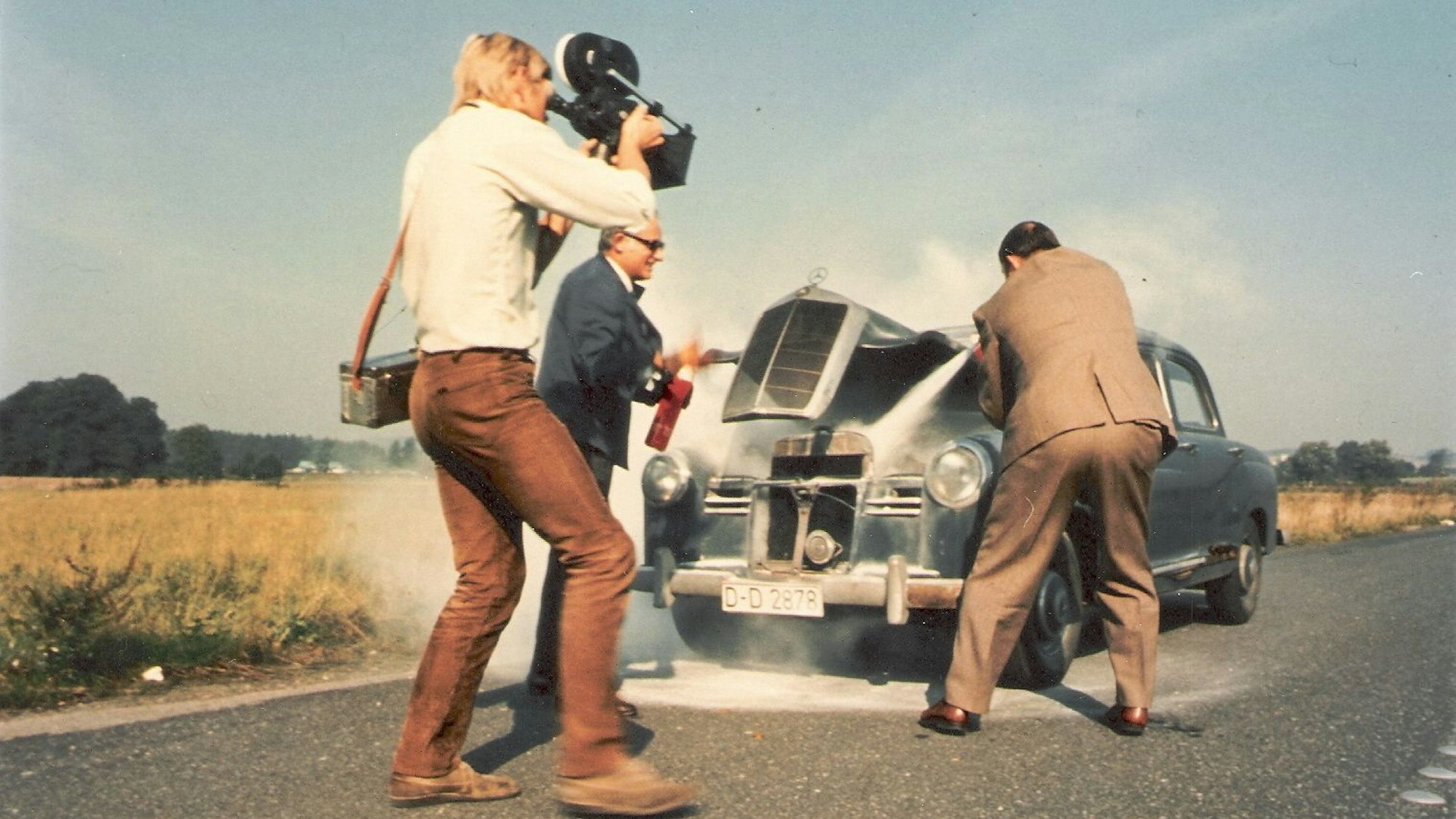 Männer löschen ein Auto, ein Kameramann filmt es.