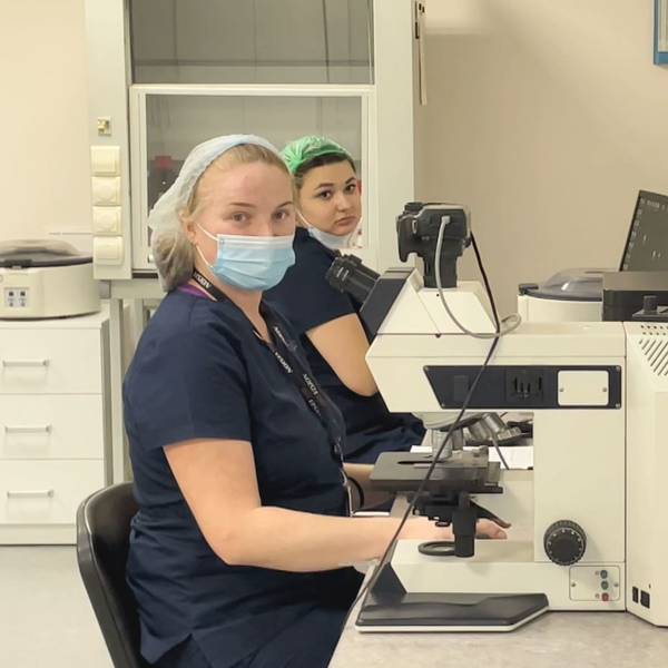 Zwei Frauen mit Mundschutz sitzen vor einem Mikroskop in der Firmenzentrale der Biotexcom-Zentrale in Kiew