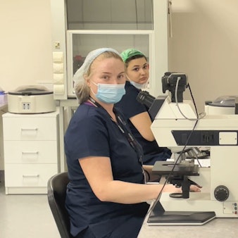 Zwei Frauen mit Mundschutz sitzen vor einem Mikroskop in der Firmenzentrale der Biotexcom-Zentrale in Kiew