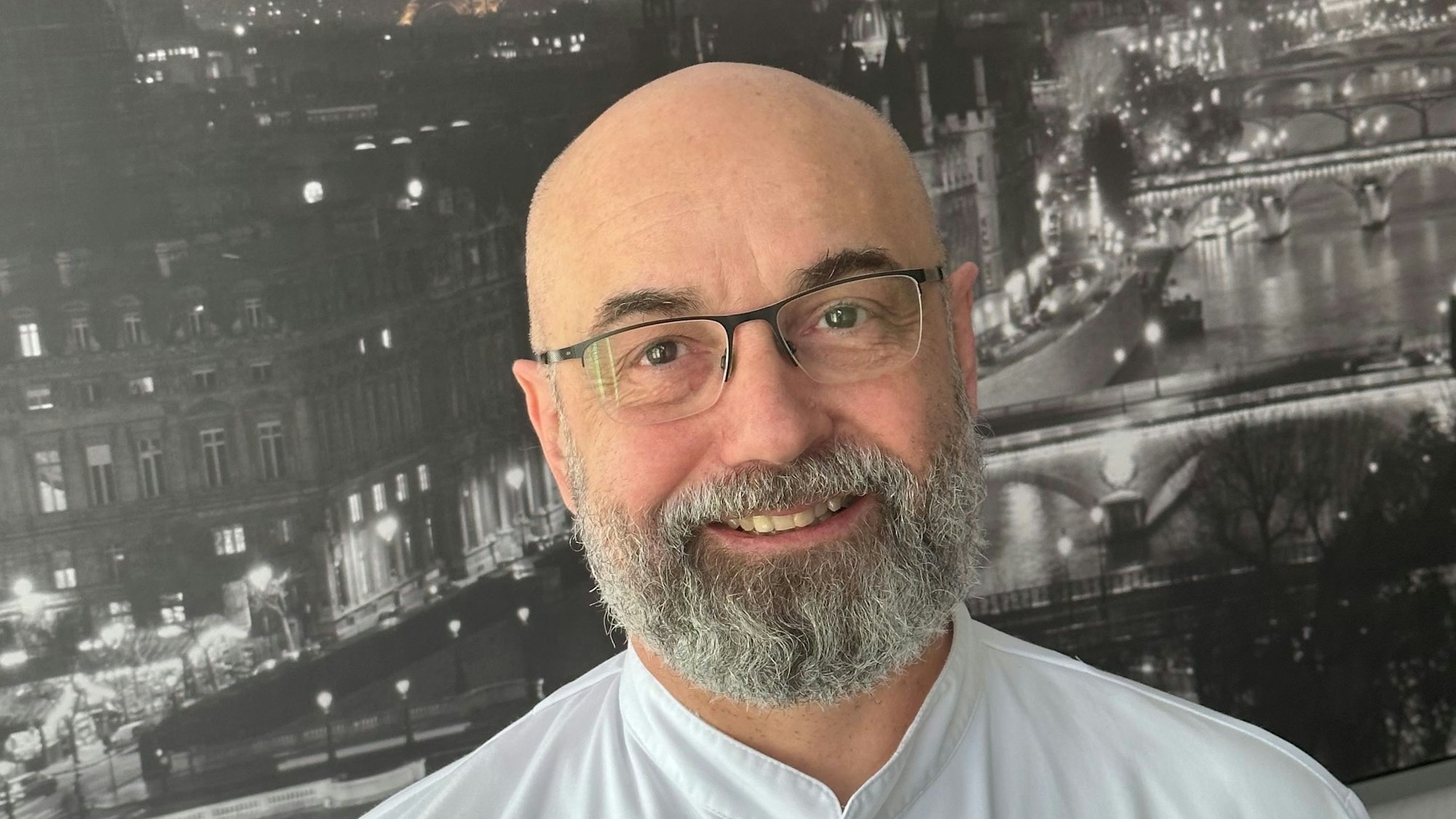 Menchon steht vor einem Bild von Paris.