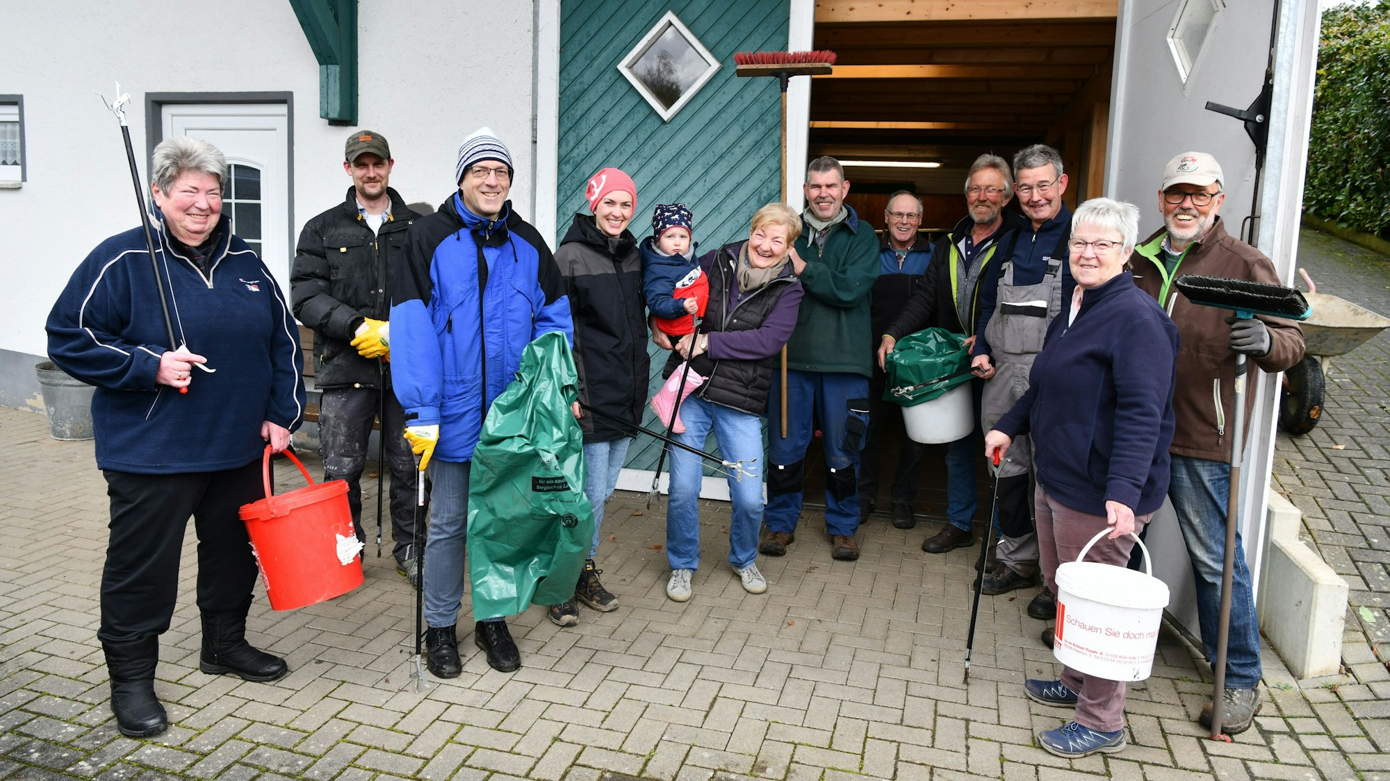 Helferinnen und Helfer stehen mit Zangen, Müllbeuteln und Eimern bereit.