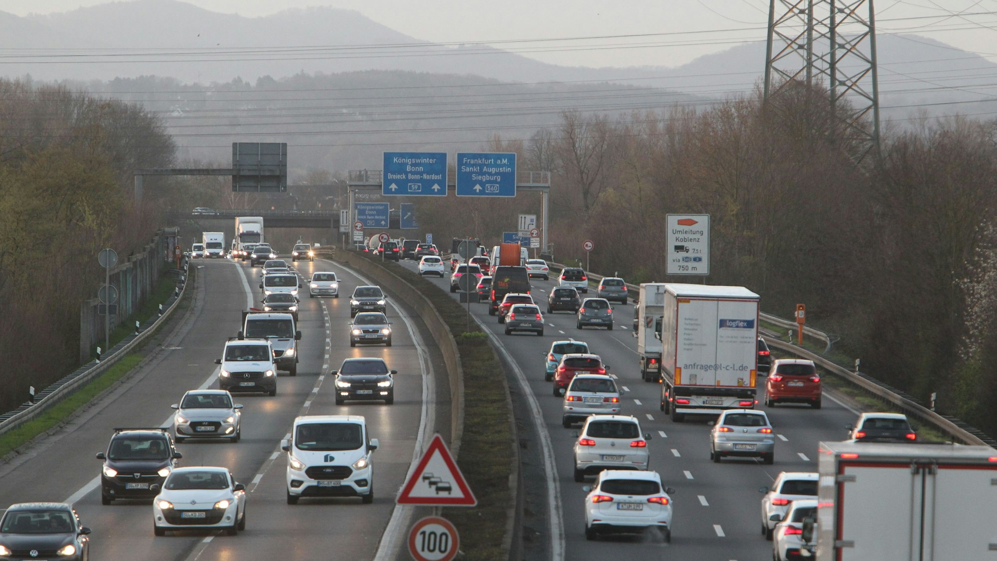 Autos fahren auf der Autobahn, im Hintergrund erhebt sich das Siebengebirge im Morgennebel.