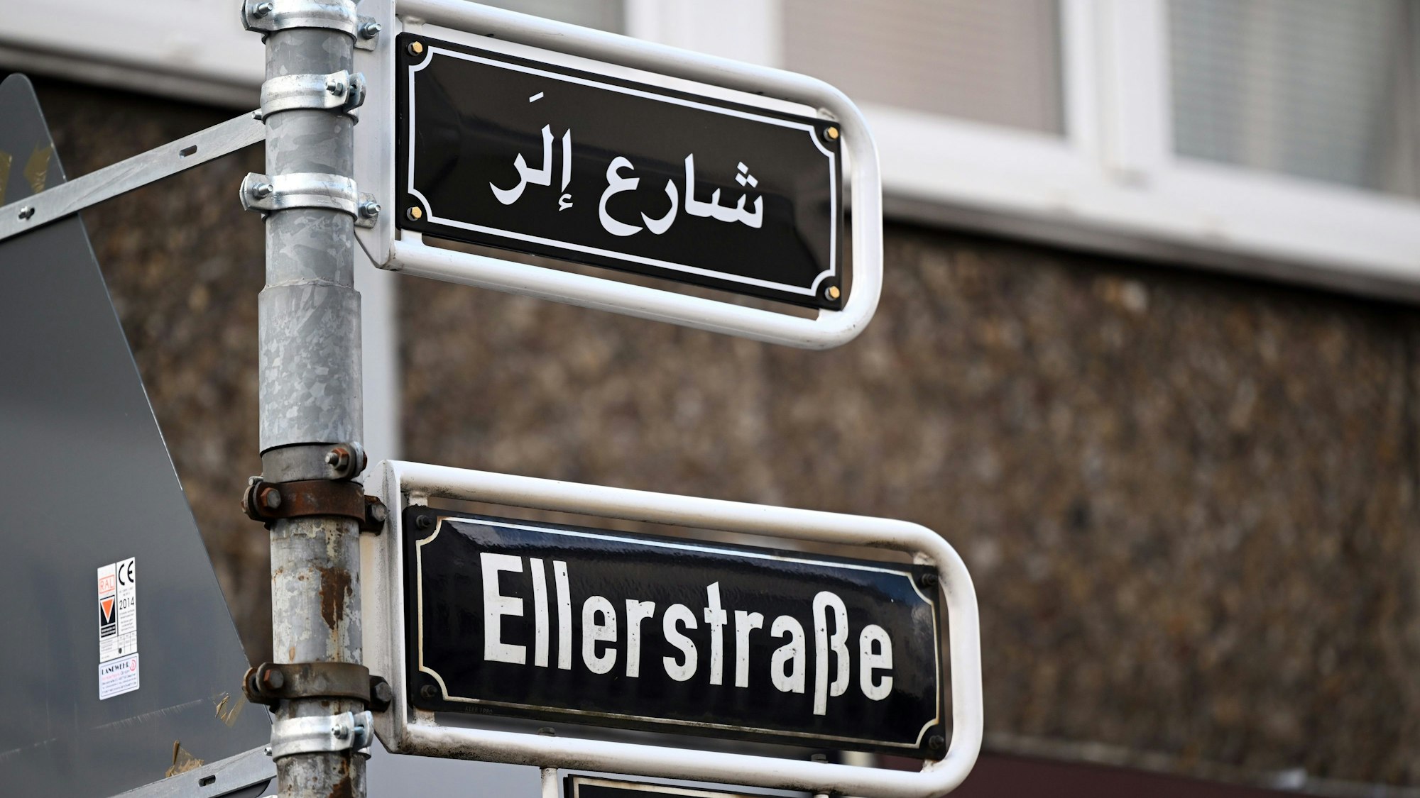 Düsseldorf: Über dem Straßenschild „Ellerstraße“ ist die arabische Version zu sehen.
