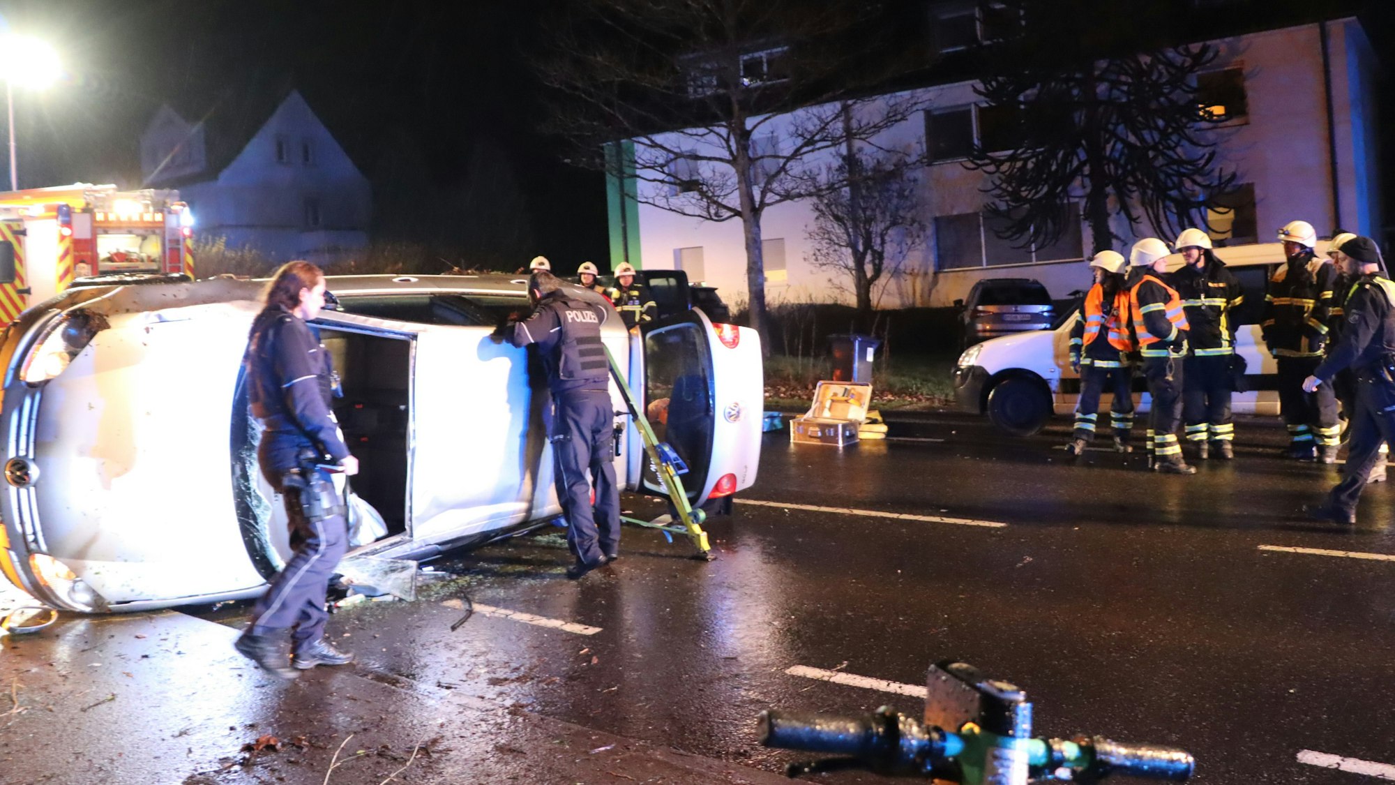 Ein auf der Seite liegender Pkw und Einsatzkräfte der Polizei und Feuerwehr.