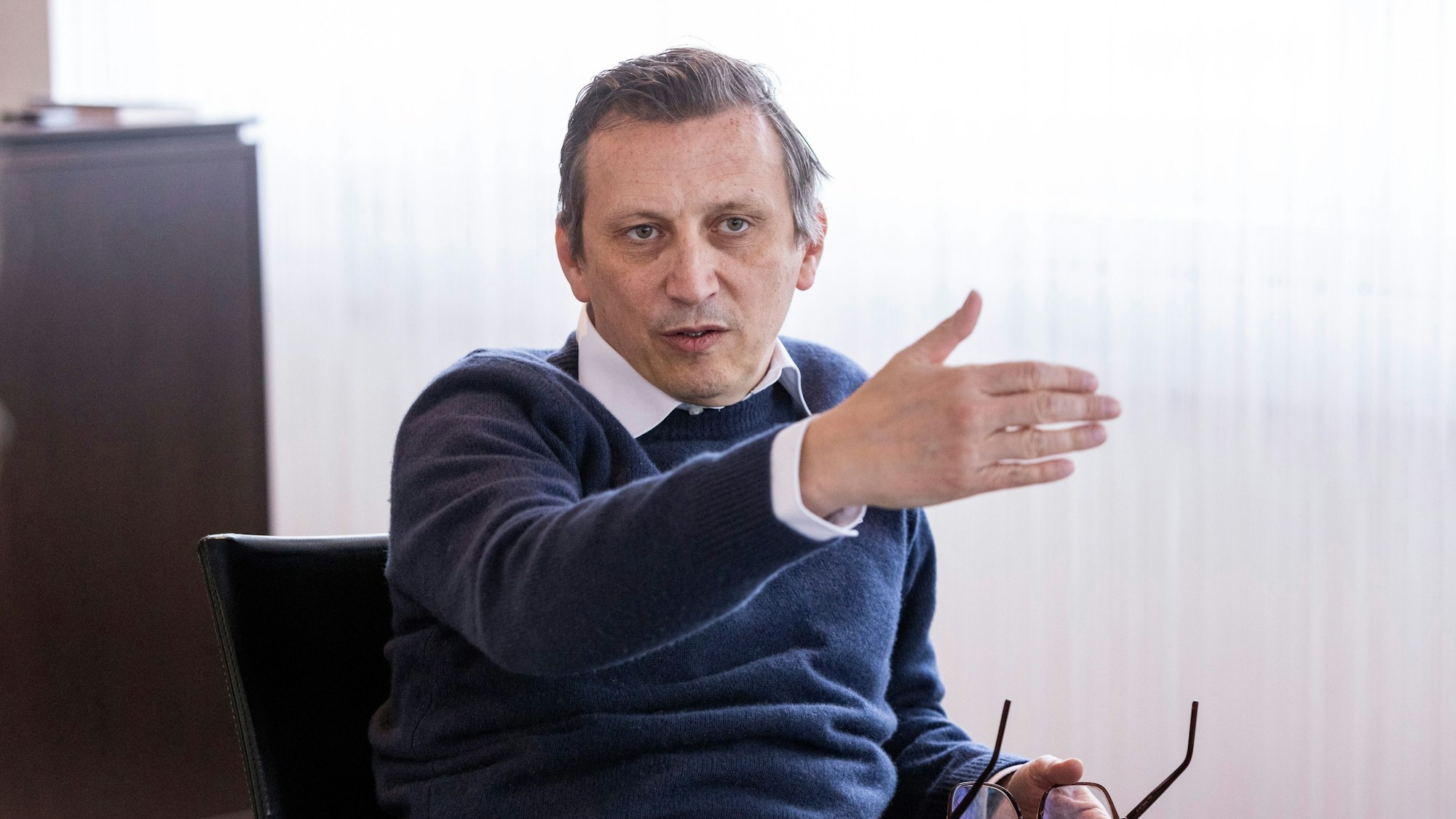 Rewe-Chef Souque sitzt an einem Schreibtisch und gestikuliert.