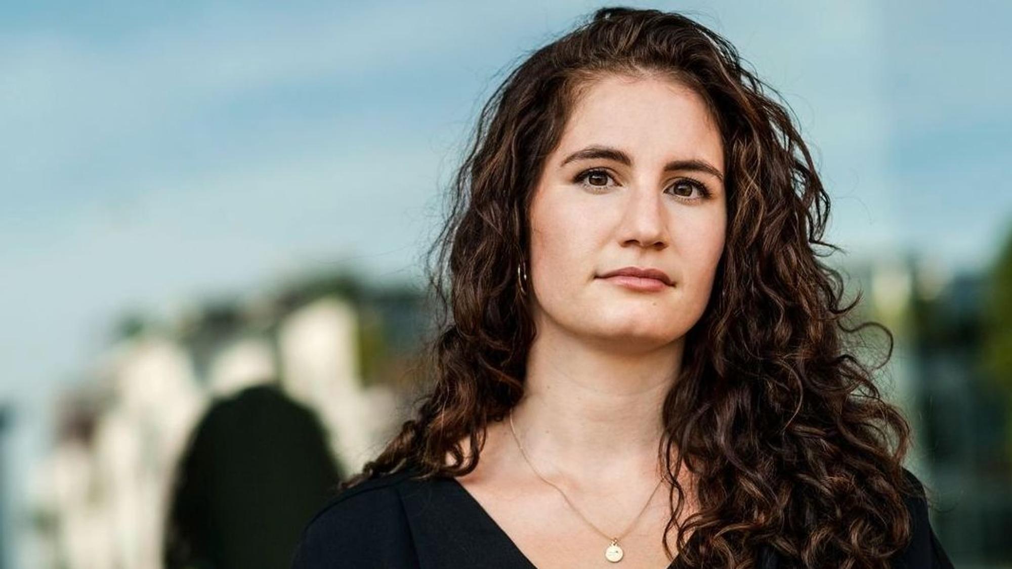 Autorin Lisa Roy hat lange gewellte braune Haare und dunkle Augen. Der Hintergrund ist verschwommen.