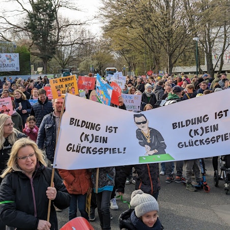 Das Bild zeigt mehrere Demonstranten mit Plakaten auf dem Weg zum Rathaus.