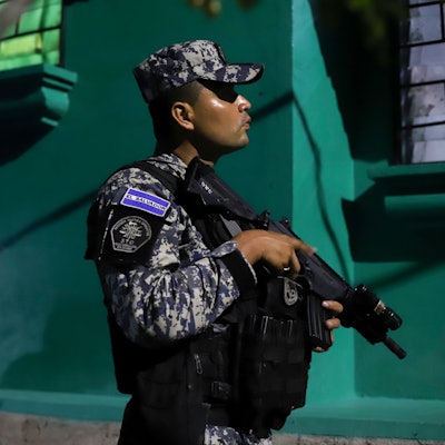 Ein Mitglied der nationalen Zivilpolizei von El Salvador hält in Tarnkleidung ein Gewehr.