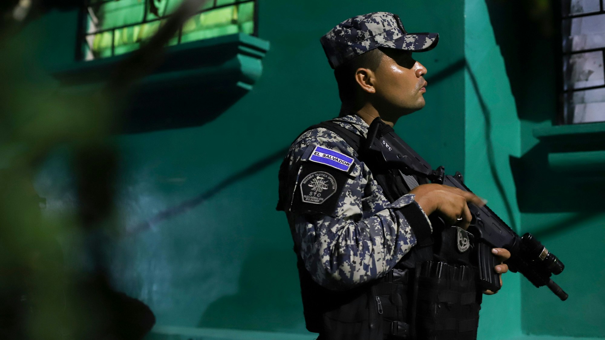 Ein Mitglied der nationalen Zivilpolizei von El Salvador hält in Tarnkleidung ein Gewehr.