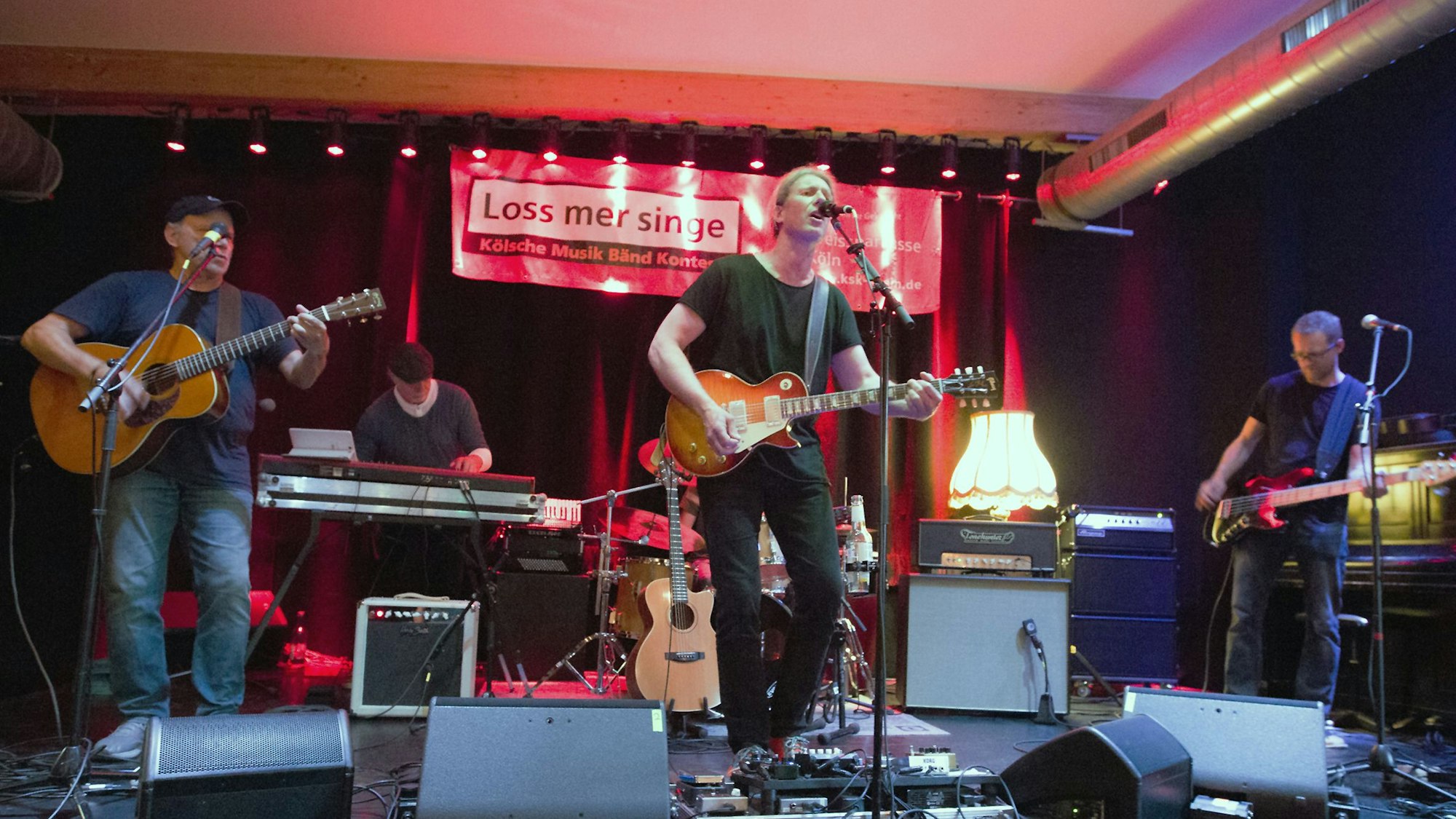 Eine Band aus vier Männern steht auf einer Bühne.