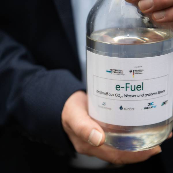 Ein Mitarbeiter einer Karlsruher Forschungsanlage hält eine Flasche mit E-Fuel. Der Kraftstoff soll trotz des Verbots für Verbrennungsmotoren eine Alternative sein.