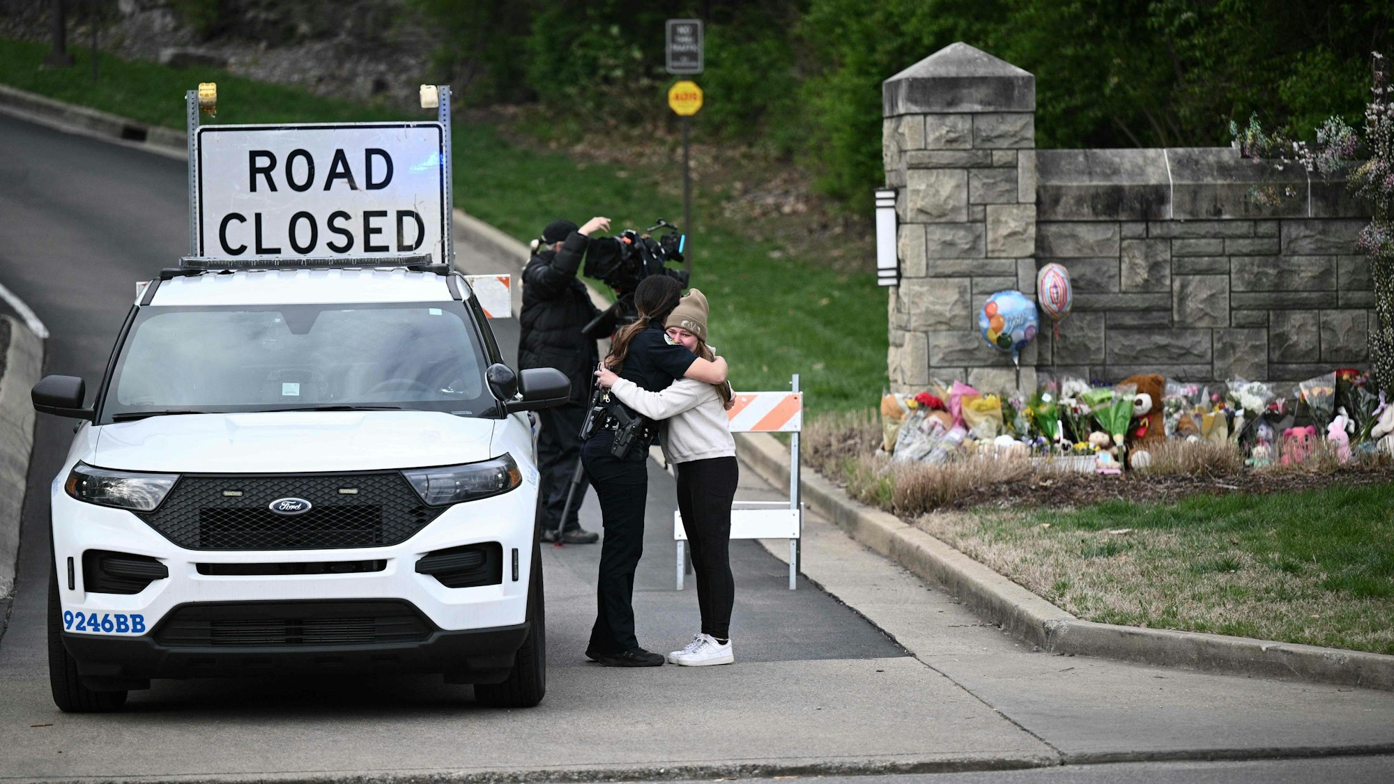 Eine Polizistin und eine andere Frau umarmen sich vor der Zufahrt zur Covenant School in Nashville, Tennessee.