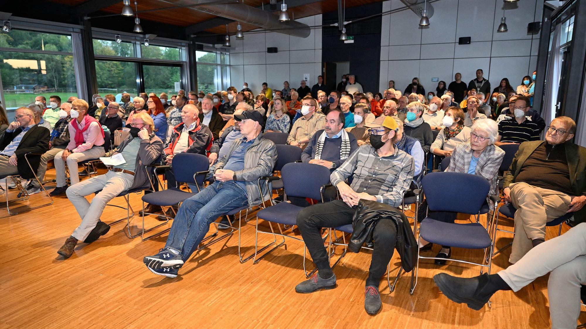 Menschen sitzen in einem Saal und schauen nach vorne.