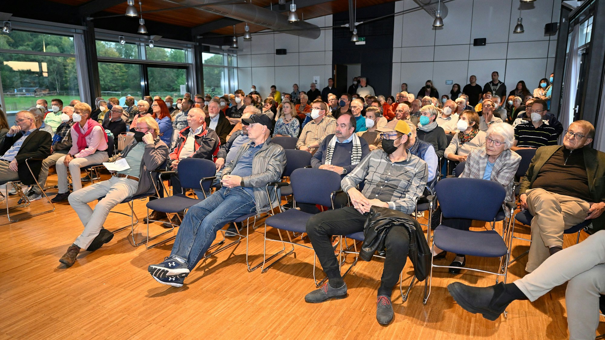 Menschen sitzen in einem Saal und schauen nach vorne.