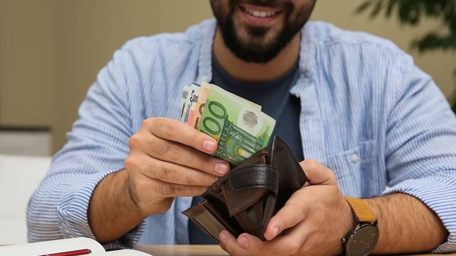 Mann zieht Euro Geldscheine aus der Geldbörse.