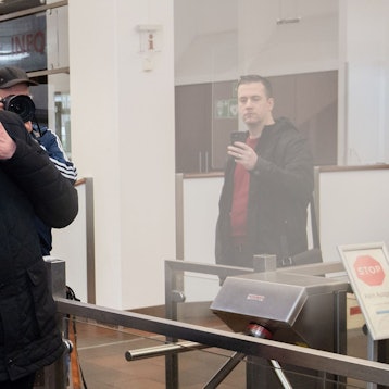 Kardinal Rainer Woelki wird im Foyer des Landgerichts von einem Justizbeamten zur Sicherheitsschleuse begleitet.