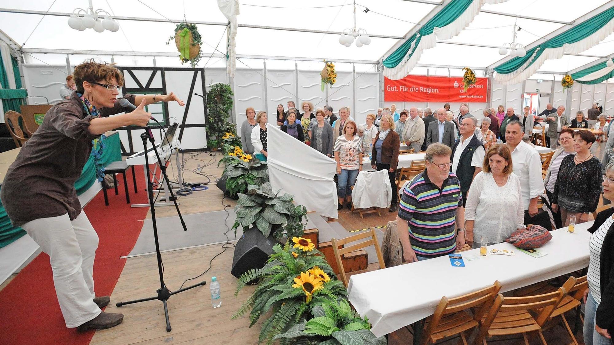 Die Kölner Musikerin Kathrin Eigendorf steht im Festzelt auf der Bühne und animiert das Publikum zum Mitsingen.