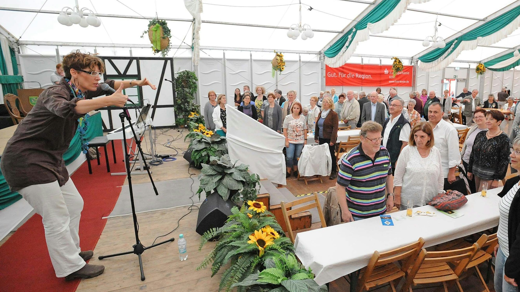 Die Kölner Musikerin Kathrin Eigendorf steht im Festzelt auf der Bühne und animiert das Publikum zum Mitsingen.
