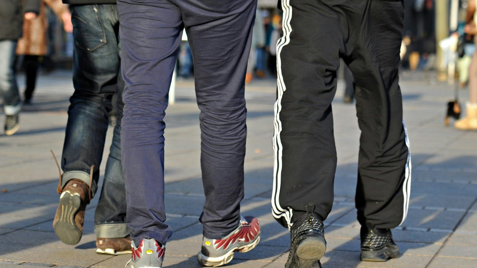 Baden-Württemberg, Stuttgart: In Jogginghosen gehen junge Männer die Königstraße entlang.