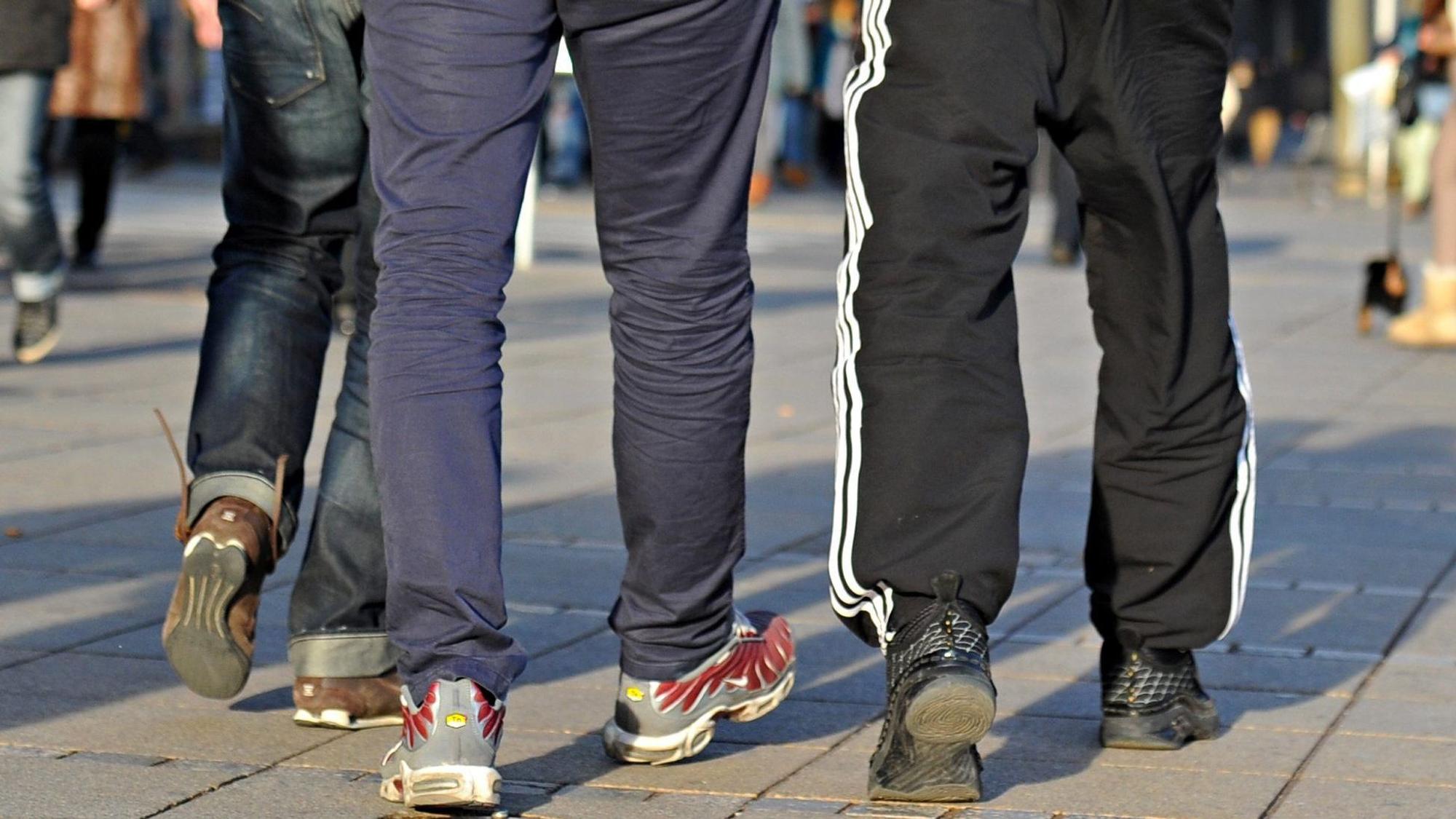 In Jogginghosen gehen junge Männer die Königstraße entlang.