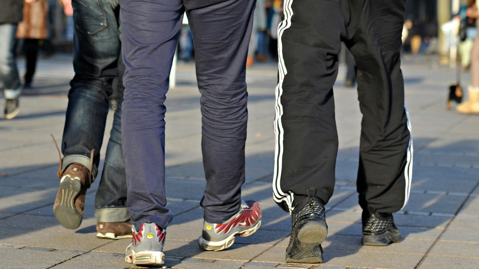 In Jogginghosen gehen junge Männer die Königstraße entlang.