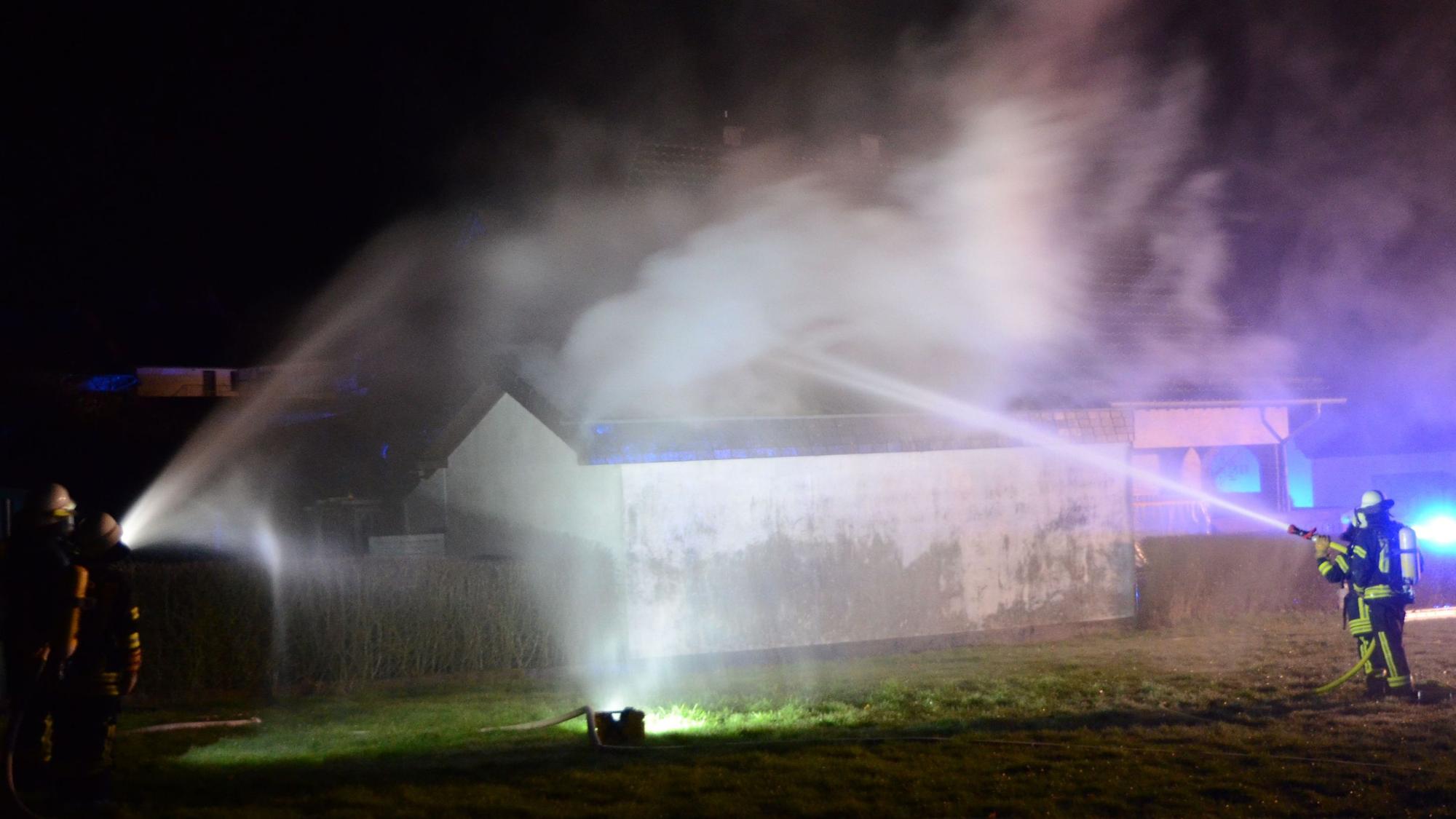 Das Foto zeigt Feuerwehrleute, die den Brand mit ihren Strahlrohren bekämpfen.